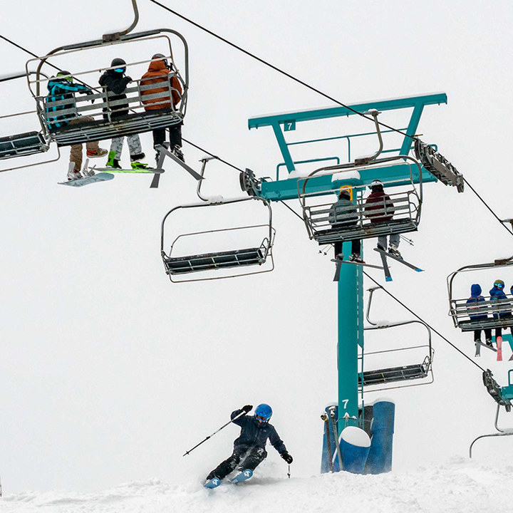A skier making a turn onto the head wall of Eagle with people on a chairlift watching.