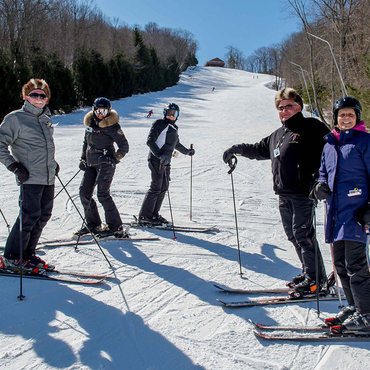 group of adults with furry hats standing on ski slope