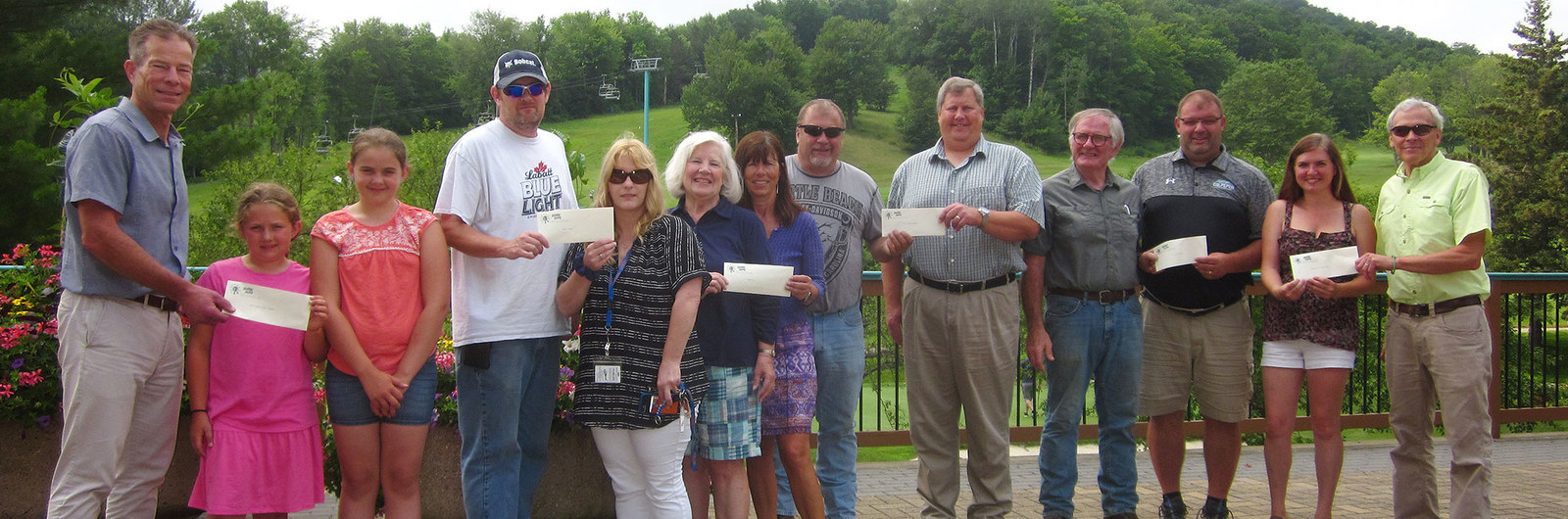 Group photo of people holding checks that will be donated to charity