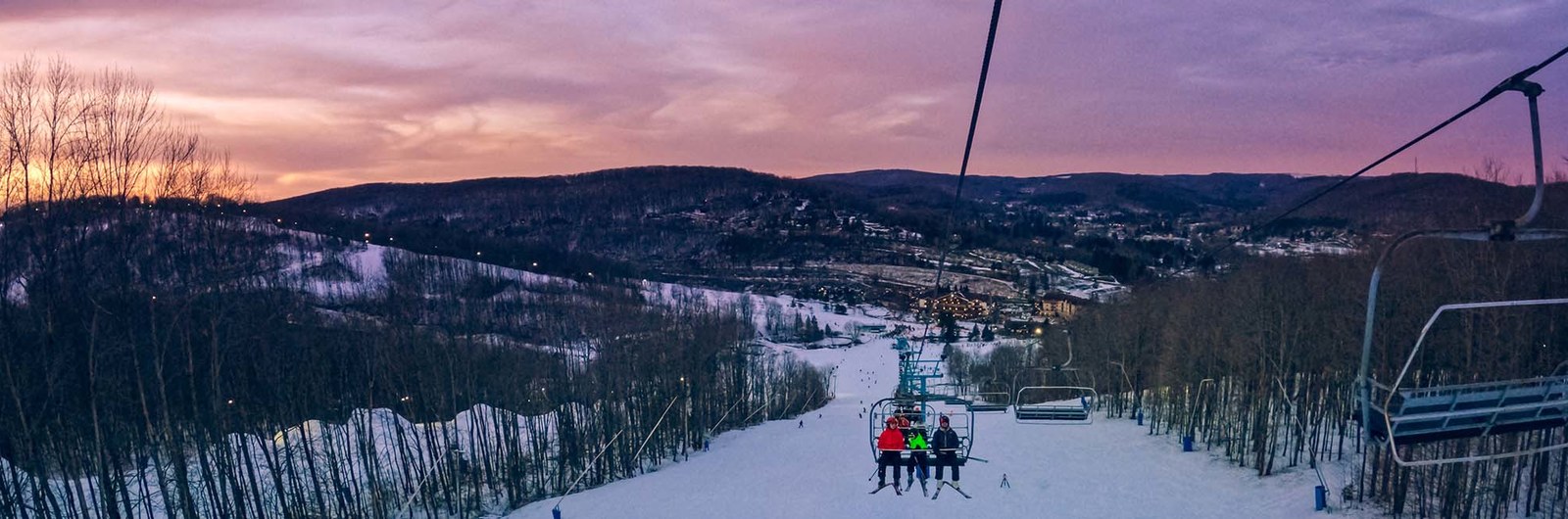 People riding a chairlift with a beautiful sunset in the background