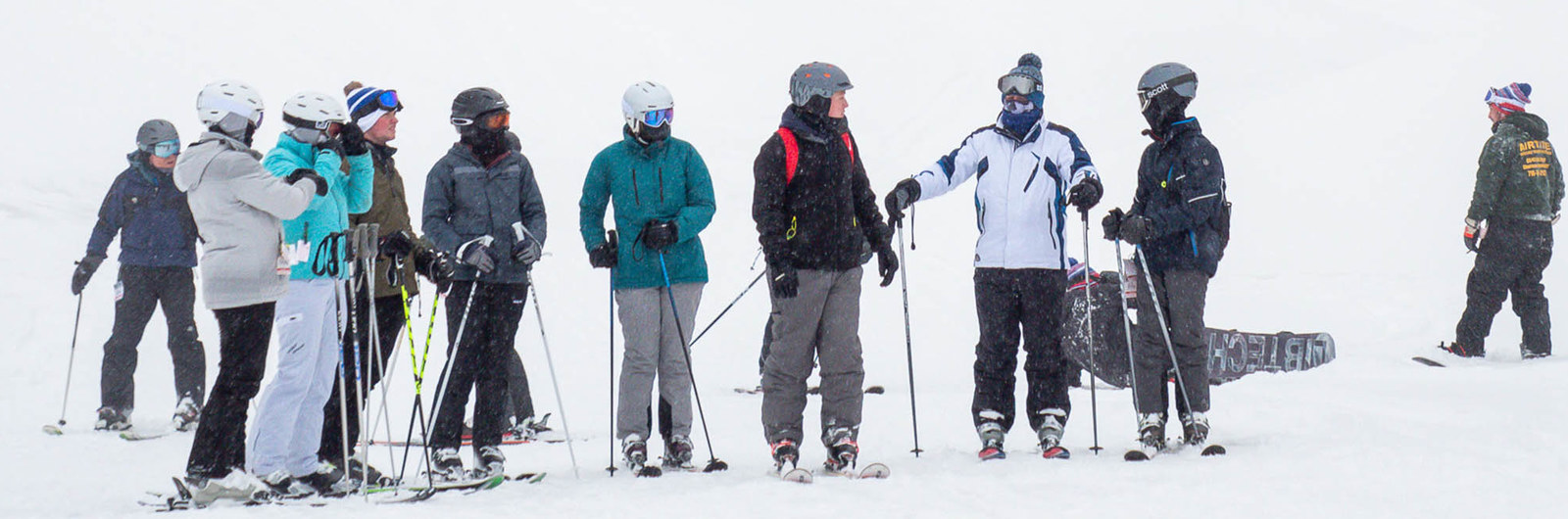 A group of skiers standing at the bottom of a hill.