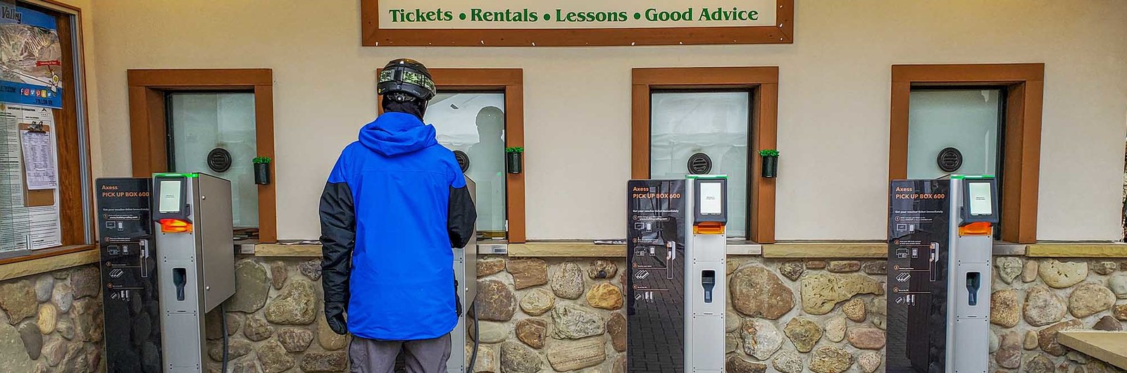 A man standing at a PUB machine getting his lift tickets.