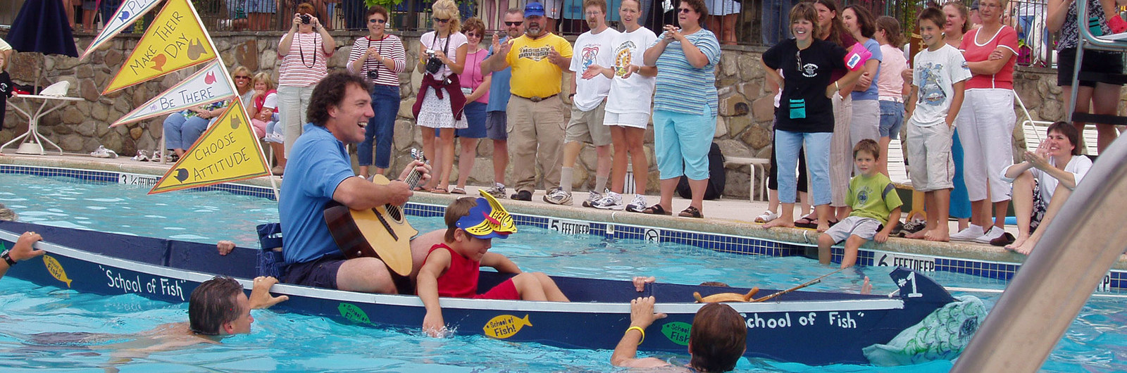 Man playing guitar in a boat in the pool at a team building event