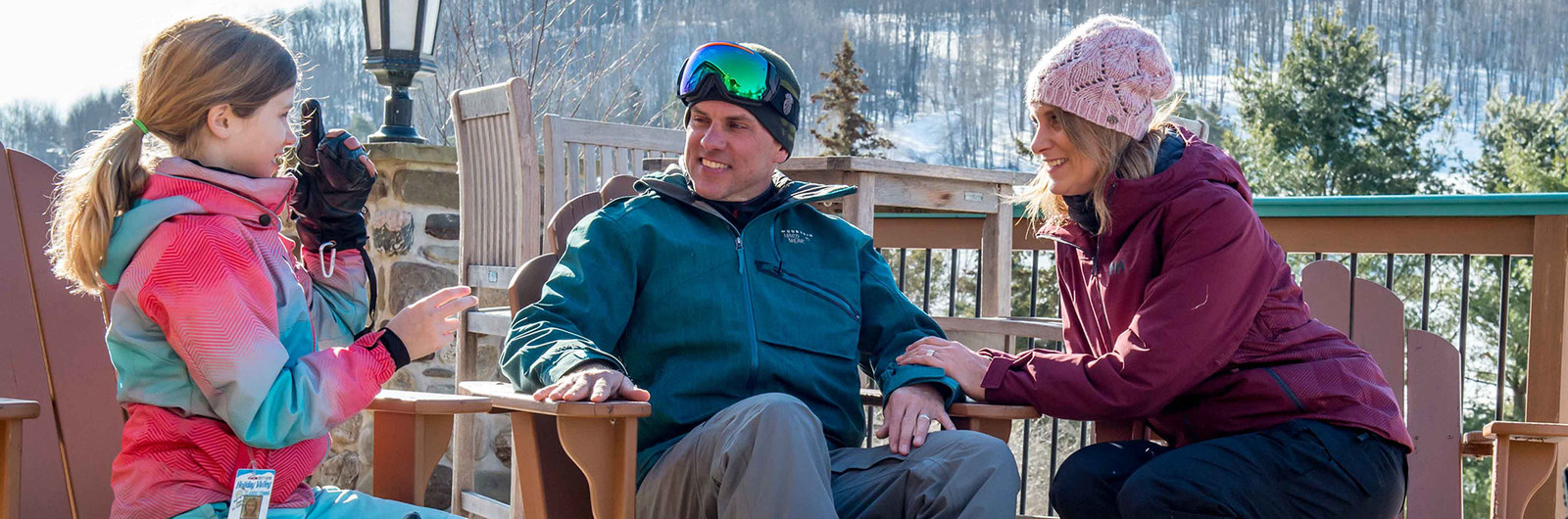 Mom and dad sitting with child outside at ski resort