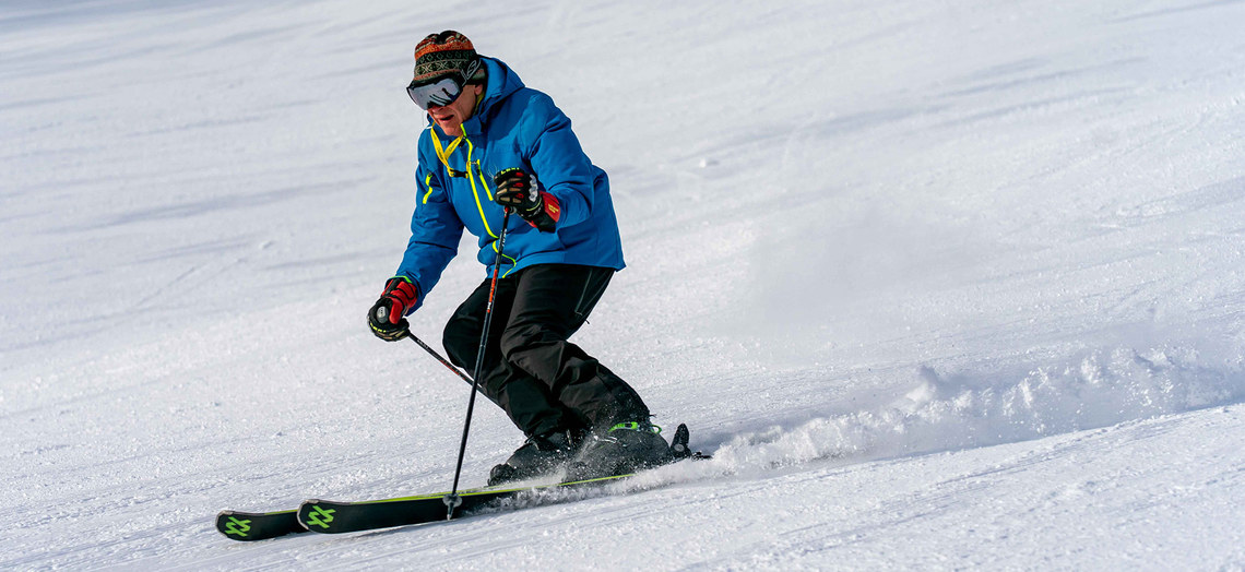 Dennis Eshbaugh on skis making a dynamic turn.