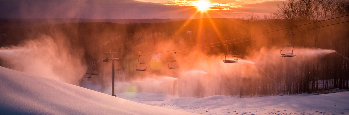 A beautiful early morning sunrise on the Morning Star run with snowmaking guns making snow.