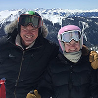 Andy Minier standing with a woman in ski gear at the top of a mountain.