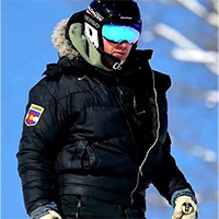 Andy Minier in ski attire standing on a slope with a blue sky in the background.