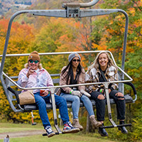 Three guests riding a chairlift at the annual Fall Festival.