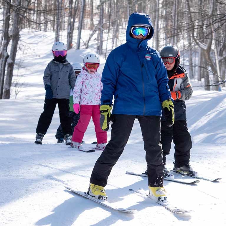 Instructor on skis with four children.