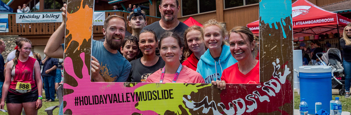 A group of Mudslide runner pose for a photo inside a large novelty photo frame.