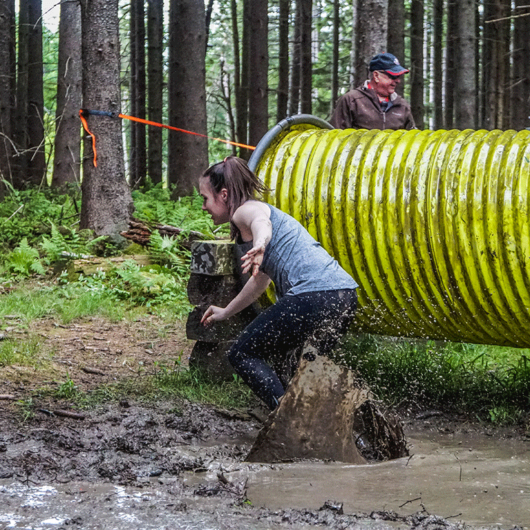 girl landing in mud after an obstacle on the trail run