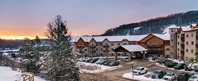 A sunrise view of the exterior of the Tamarack Club in the winter.