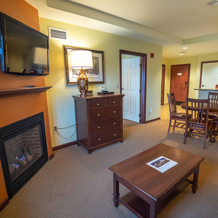 Interior view of a living room area in the Tamarack Club with a TV above a fireplace.