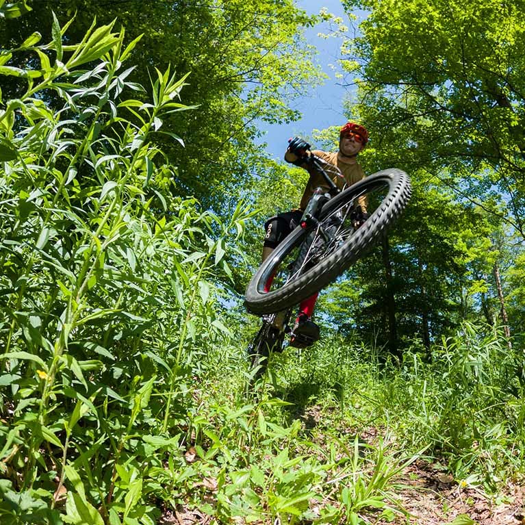 Man catching air, riding a mountain bike through the forest