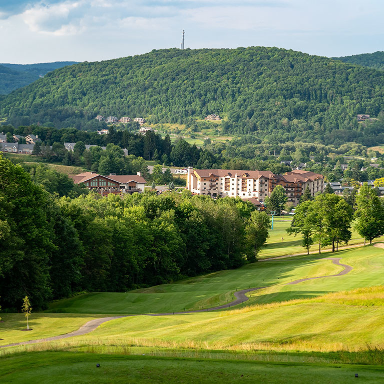 View of Holiday Vallery ski lodge surrounded by green hills and trees during the Summer
