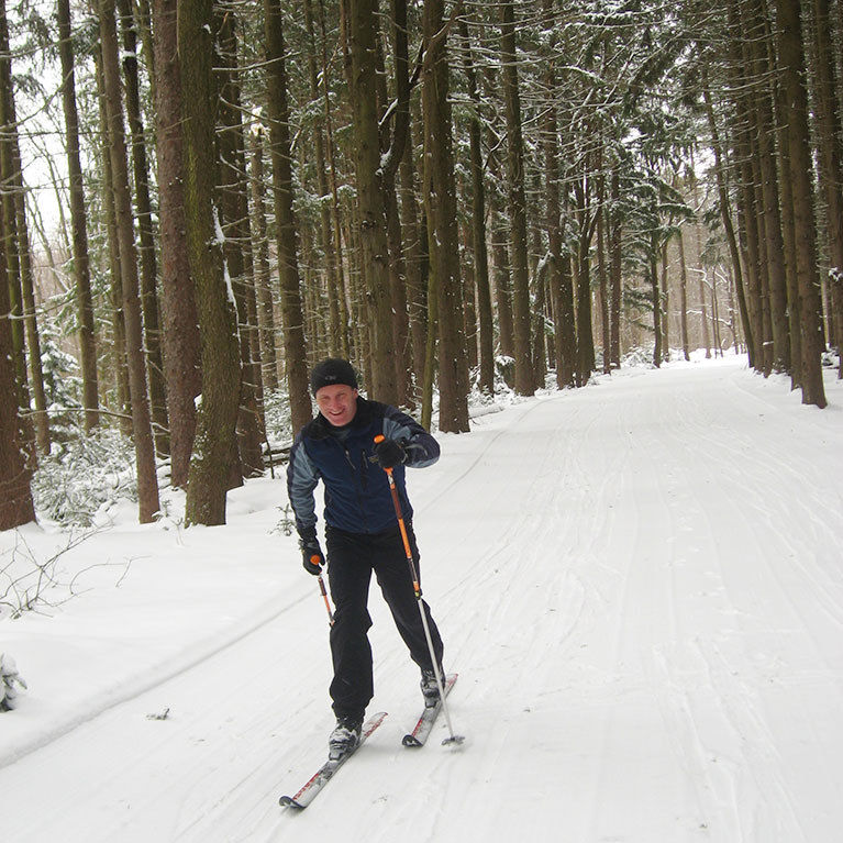Man cross country skiing on trail through the woods